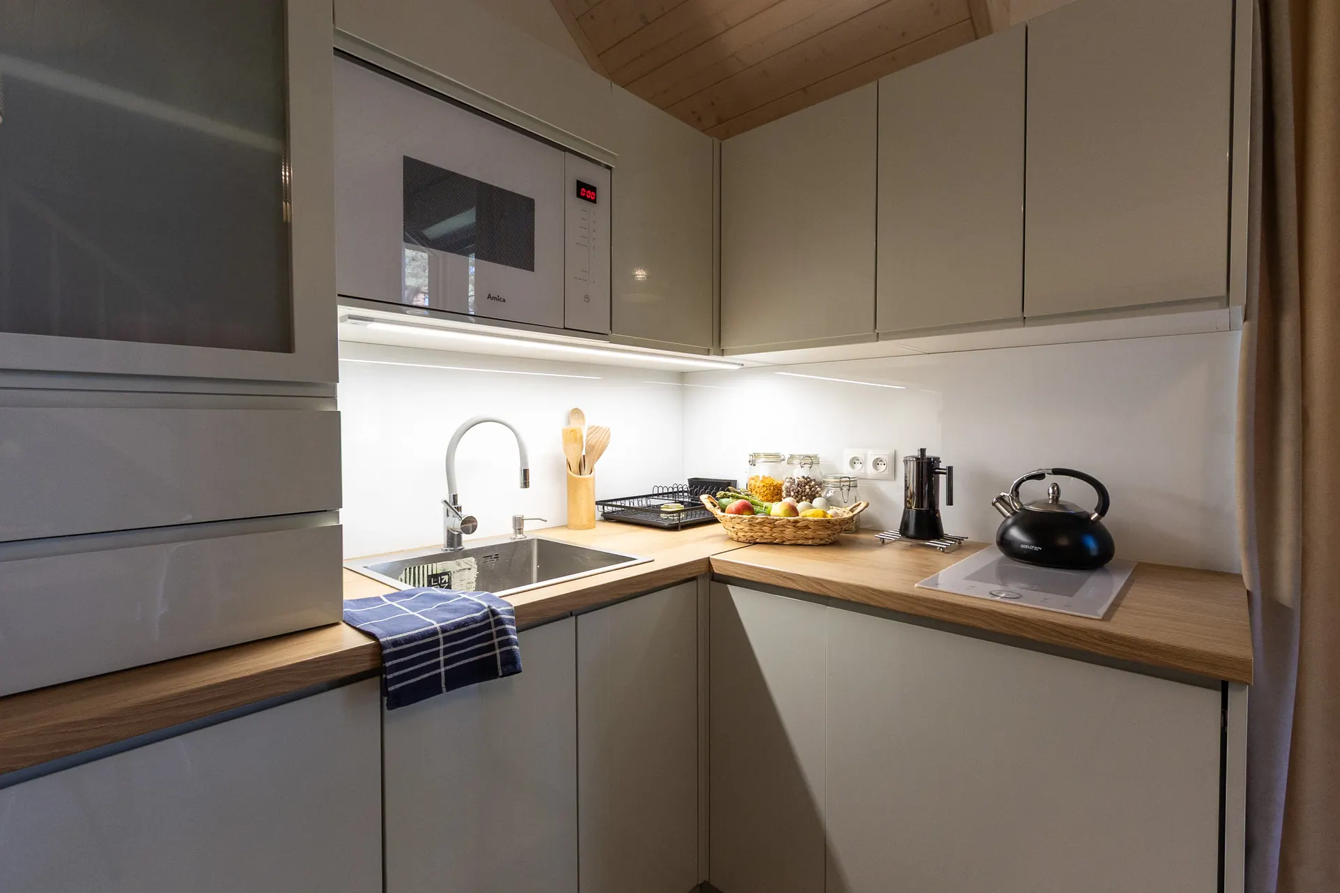 Aneks kuchenny z szarymi szafkami, mikrofalą i drewnianym blatem — Apartament 2 Poezja Ciszy Dębki